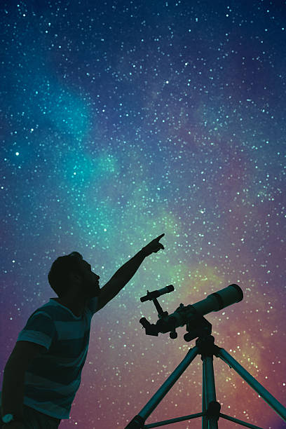 istock Man looking at the stars with telescope beside him. 618651220