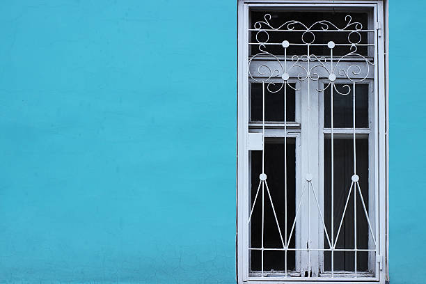 istock Bright blue wall and white old window with bars. Minimalism 618721274