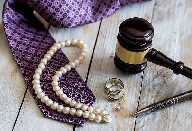 Divorce law concept. Judge gavel, rings, tie and pearl necklace stock photo