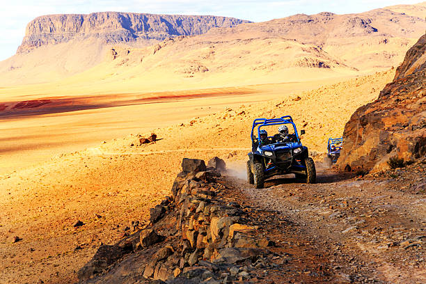 polaris rzr 800 bleu traversant une route de montagne - off road vehicle quadbike desert dirt road photos et images de collection