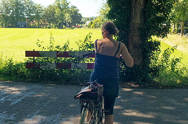 Woman with bicycle standing on cycle path on countryside. Winterswijk.