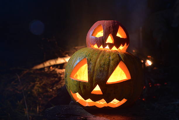 istock two halloween pumpkins jack faces in the dark forest on 618725166