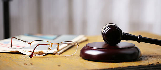 Labor law concept, gavel, glasses and newspaper on wooden table stock photo