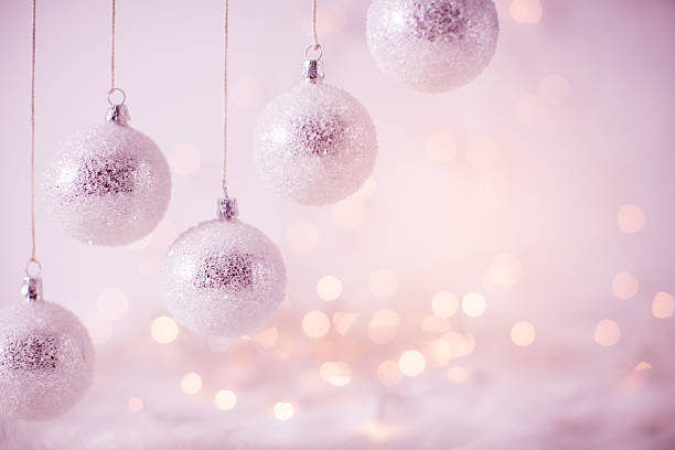 Christmas ornaments hanging on string. Defocused string lights in background. Pink toned image.