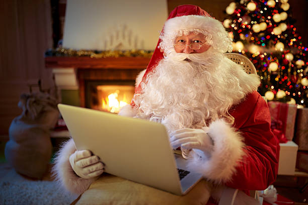 istock Santa Claus sitting by the fireplace with laptop 618733080