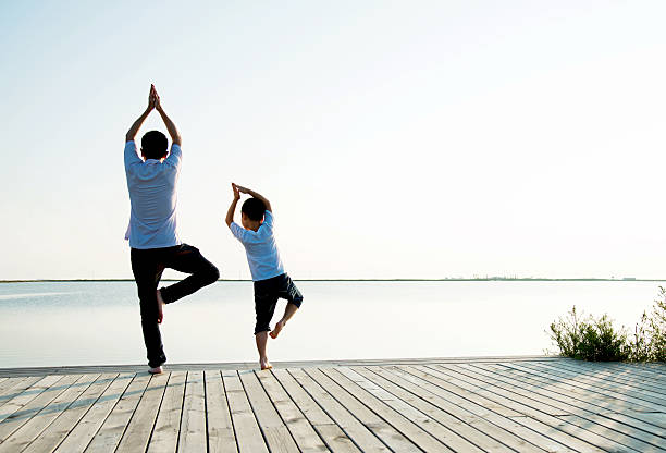 istock Father with his son doing yoga by the lake 618734580