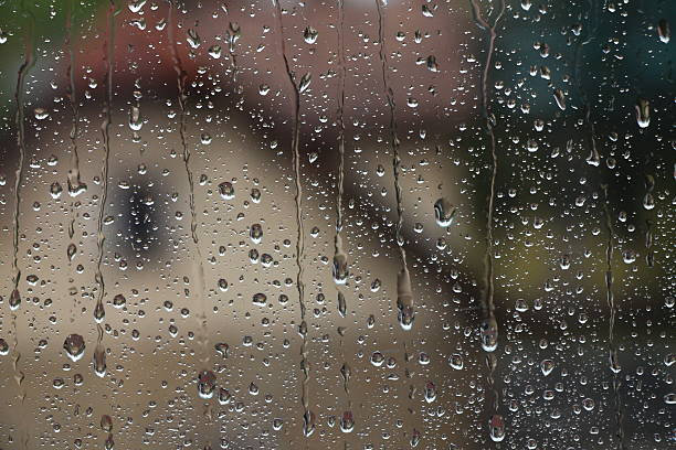 istock Rain drops on window with house and church in background 618739184