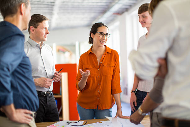 jovens profissionais se reunindo em torno de uma mesa - small business manager designer partnership - fotografias e filmes do acervo