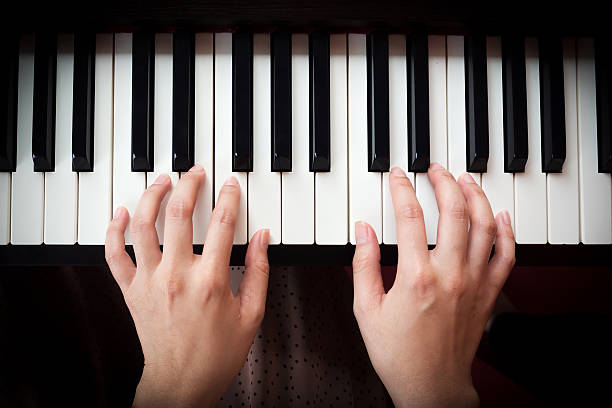 Woman's hand playing piano. Closeup woman's hand playing piano. Favorite classical music. Top view with dark vignette. piano key stock pictures, royalty-free photos & images