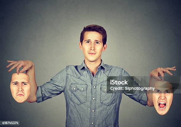 Man Holding Two Different Emotion Masks Stock Photo - Download Image Now - Control, Emotion, Artificial