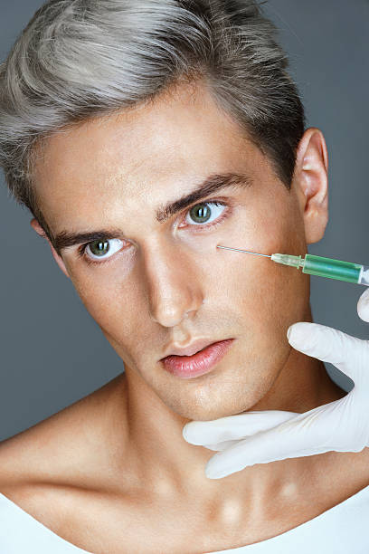 schöne junge mann bekommt schönheit injektion - plastic surgery botox injection face lift nose job stock-fotos und bilder
