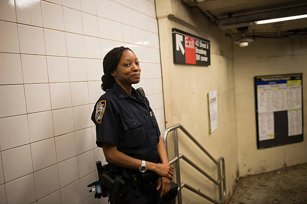 NYPD officer in Times Square subway station, New York New York City, USA - July 9, 2016: Late at night, a New York City police officer stands inside the entrance to a subway station in Times Square in New York City. female police officer stock pictures, royalty-free photos & images