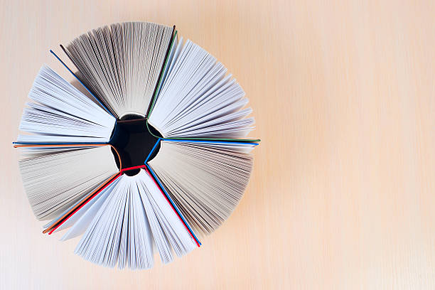 istock Open book, stack of hardback books on wooden table. 618748564