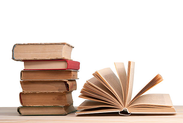 istock Open book, stack of hardback books isolated on wooden table. 618748834