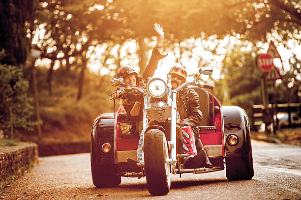 couple d’adultes sur trike profitant d’une promenade au coucher du soleil - tricycle photos et images de collection