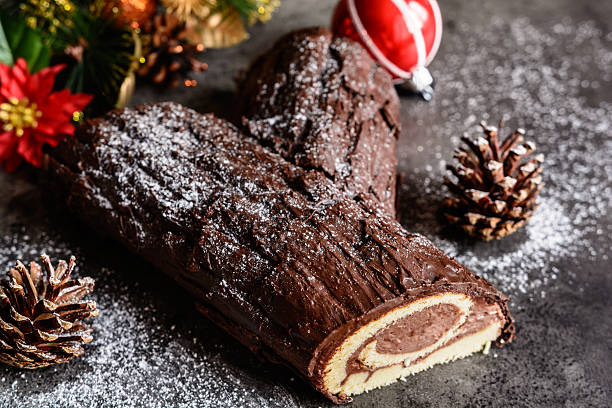 Traditional Christmas Buche de Noel cake Buche de Noel - traditional French Christmas cake sprinkling powdered sugar stock pictures, royalty-free photos & images