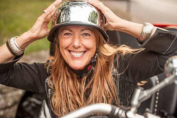 mujer que se pone un casco de motorista de estilo vintage - motorcycle women helmet sensuality fotografías e imágenes de stock