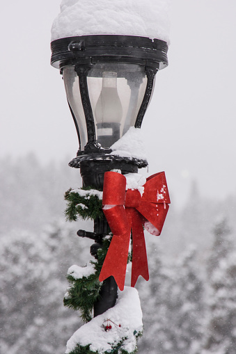 A lamp post decorated for Christmas and covered in snow