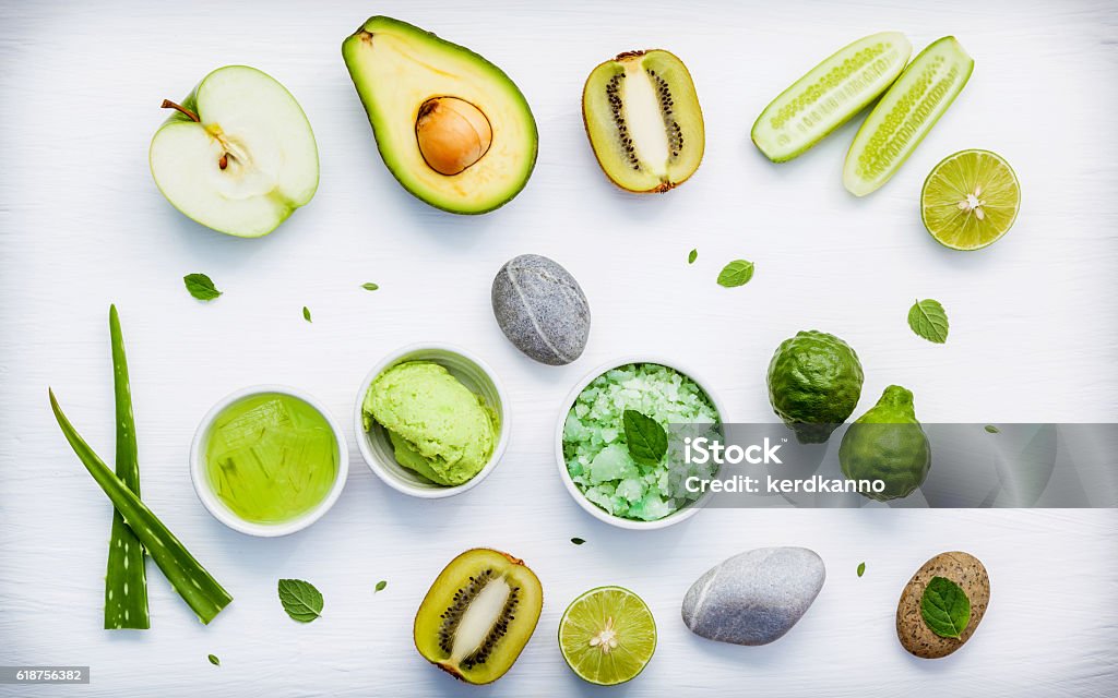 Homemade skin care and body scrubs with green natural ingredient Homemade skin care and body scrubs with green natural ingredients aloe vera ,lime,cucumber ,aromatic salt ,green apple,mint ,rosemary ,kiwi and sage set up on white wooden background with flat lay. Antioxidant Stock Photo