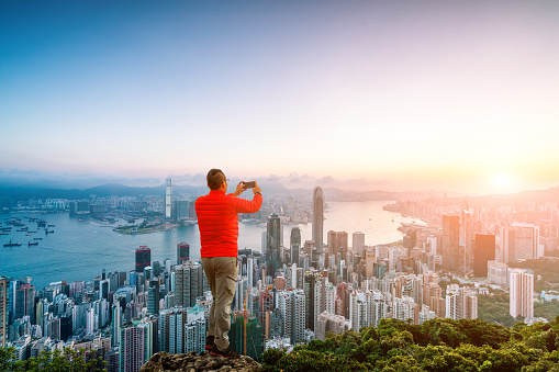 man climbing to the rock facing Hong Kong skyline