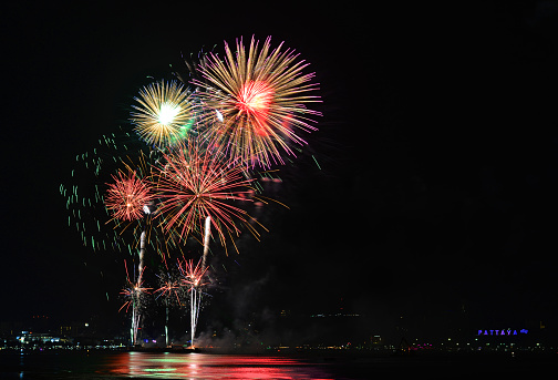 Multicolor fireworks night scene, closeup with pattaya cityscape sea beach view, thailand