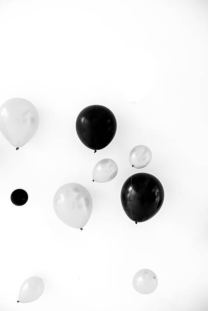 A floating balloon in the air inside a party room with backdrop in the background, in black and white