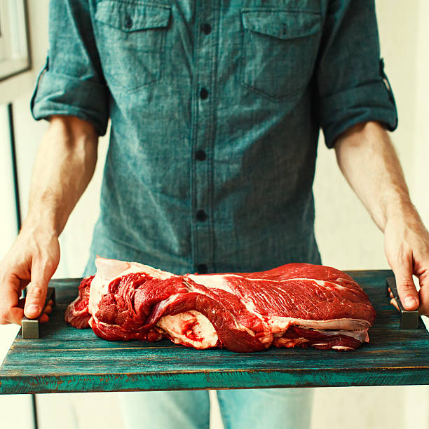 istock Man`s hands holding  rustic tray with raw beef meet 618827908