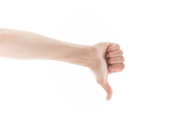 Close up of woman making thumbs down sign against white background.