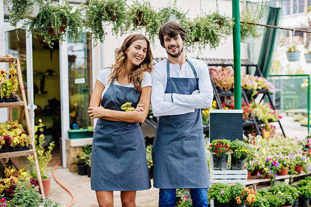 Garden center owners Young couple running a garden center, standing at the entrance, smiling and looking confident. farm produce storage stock pictures, royalty-free photos & images