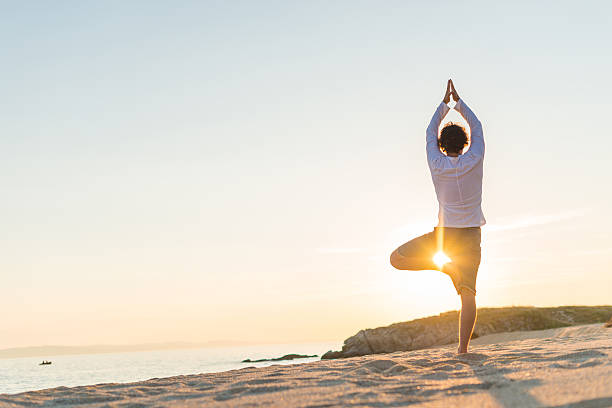 istock Practicing yoga and meditation in summer on beach in sunset 618839410