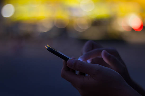 close-up hand use phone on night time in the city