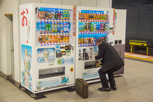 Osaka, Japan - October 26, 2016: A man buys a drink from a vending machine located at Shin-Osaka railway station.