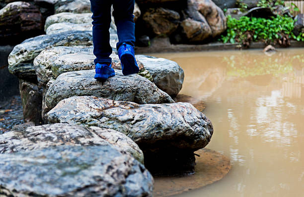 Little boy crossing stepping stones.