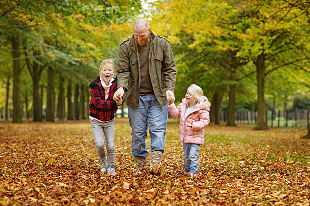 Single father and daughters walking together in autumnal park surroundings Single father and daughters walking together in autumnal park surroundings divorcee stock pictures, royalty-free photos & images