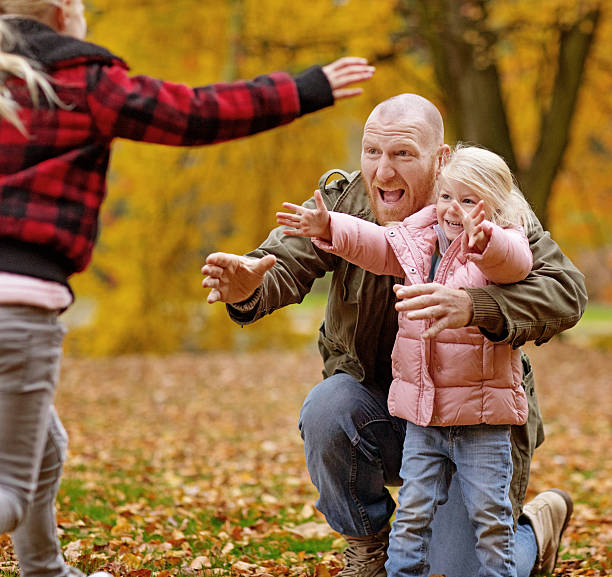 Single father and daughters playing together in autumnal park surroundings Single father and daughters playing together in autumnal park surroundings divorcee stock pictures, royalty-free photos & images