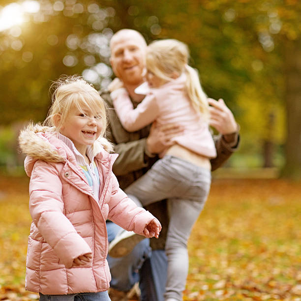 Single father and daughters playing together in autumnal park surroundings Single father and daughters playing together in autumnal park surroundings divorcee stock pictures, royalty-free photos & images