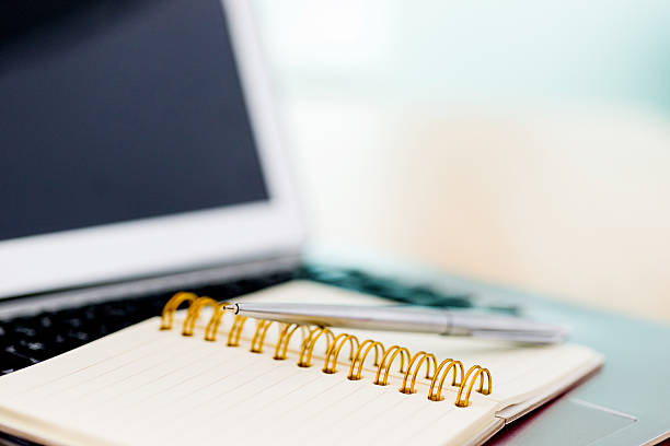 istock Laptop with pen and spiral notebook 618850882