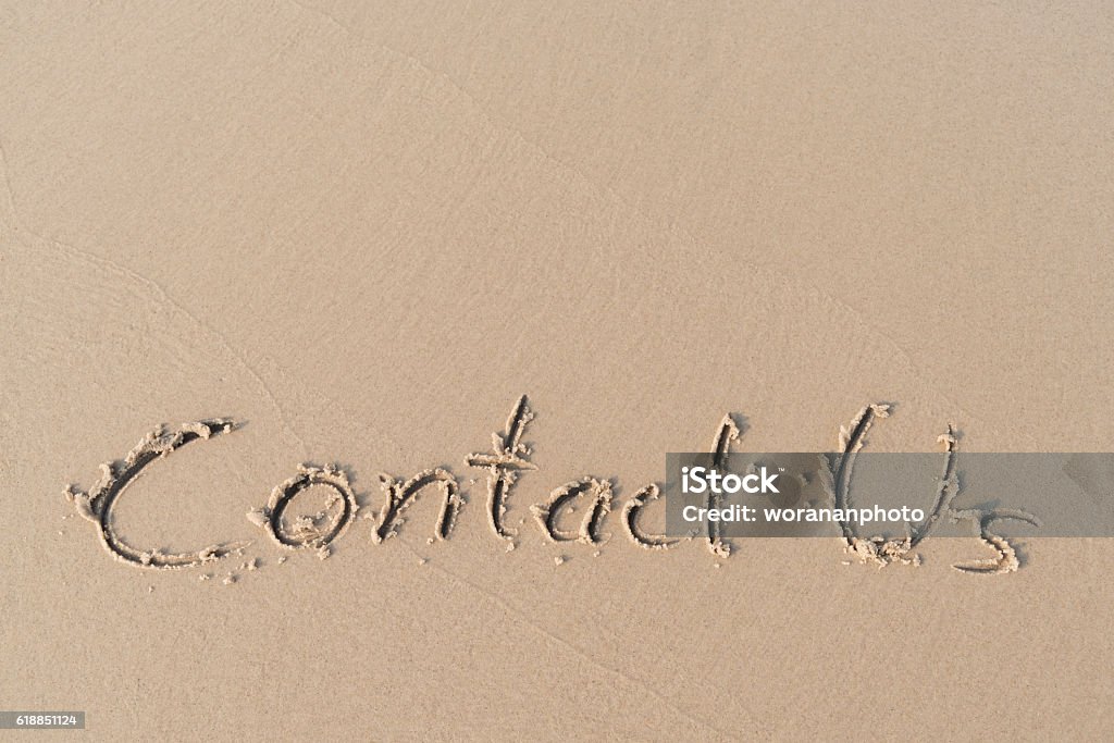 "Contact Us" message written on sand beach Contact Us Stock Photo