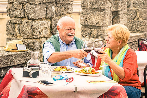 pareja de la tercera edad divirtiéndose y comiendo en el restaurante durante el viaje - couple mature adult europe travel fotografías e imágenes de stock