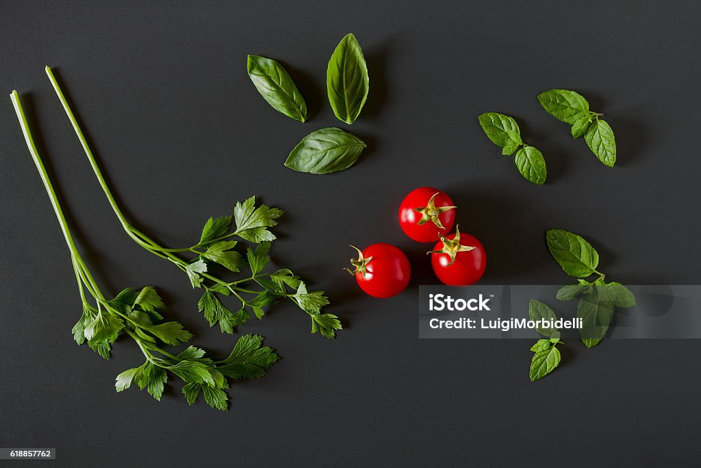 Légumes verts autour de trois tomates rouges - Photo de Fond noir libre de droits