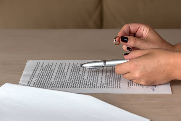 istock Hands of wife signing divorce documents, returning wedding ring 618858234