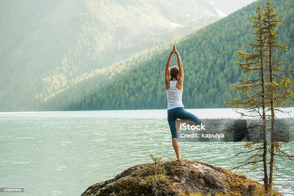 Young woman is practicing yoga at mountain lake Yoga Stock Photo