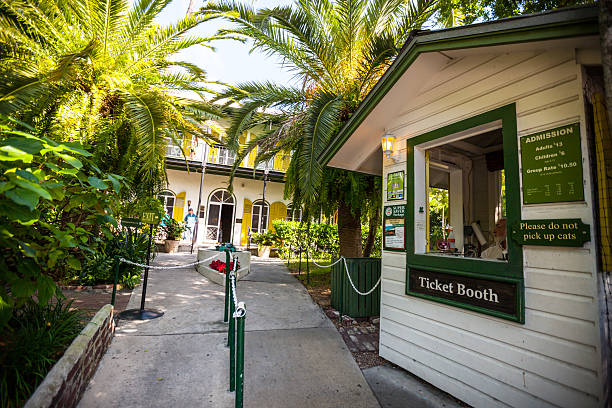 Entrance to Ernest Hemingway Home and Museum, Key West Key West, USA  - January 9, 2015: Entrance to Ernest Hemingway Home and Museum, Key West. Man inside ticket booth at the entrance, few people standing near the house hemingway house stock pictures, royalty-free photos & images