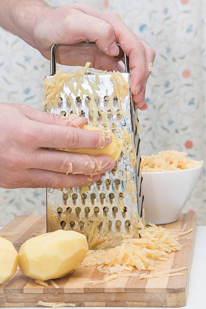 le mani dell'uomo con una grattugia grattugiano le patate. mangiare sano. - grater foto e immagini stock