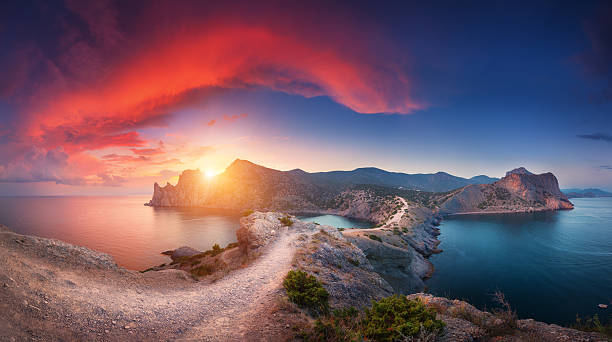 Panoramic landscape with mountains, sea and beautiful sky in summer Amazing summer landscape with mountains, sea, blue sky, sun and beautiful colorful red clouds at sunset in Crimea. Sunset in mountains. Panoramic. Nature background. Vibrant landscape in twilight. crimean mountains stock pictures, royalty-free photos & images