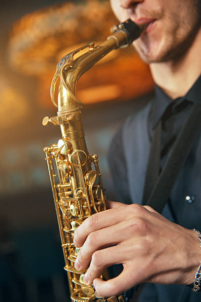 istock Young man in a suit hold saxophone 618869584