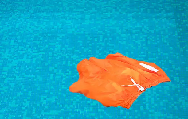A pair of mens swimming shorts floating on the surface of a swimming pool