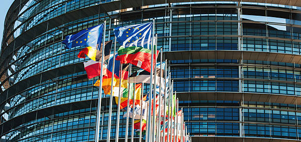 banderas de la ue frente al parlamento ondeando en el viento - european community european union flag europe flag fotografías e imágenes de stock