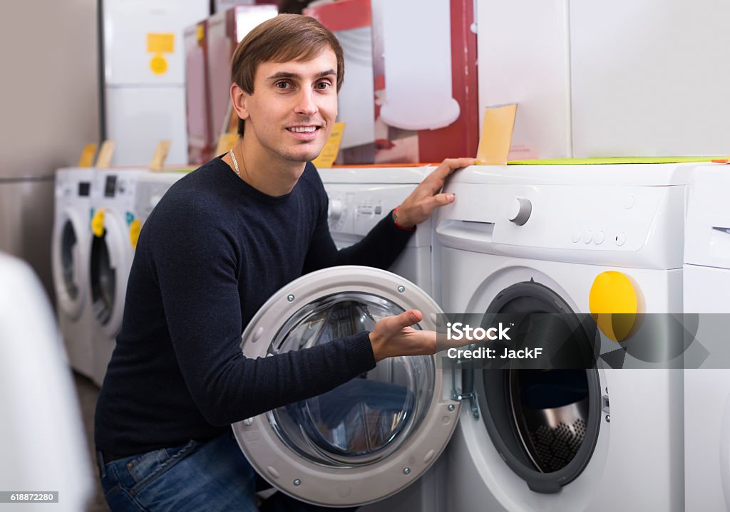 Man choosing new laundry machine Smiling young male customer looking at washers and dryers in store 25-29 Years Stock Photo