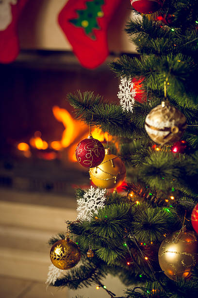 istock Closeup of decorated Christmas tree in front of burning fireplac 618872934